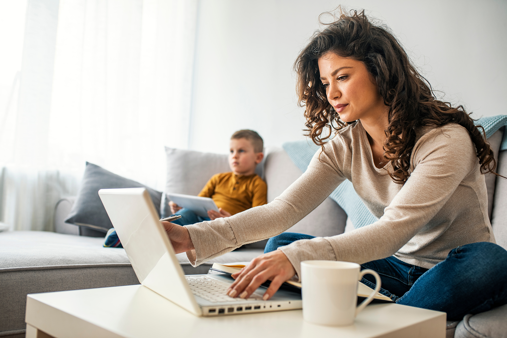 automation miling mom working at home with her child on the sofa while working on automating her business.