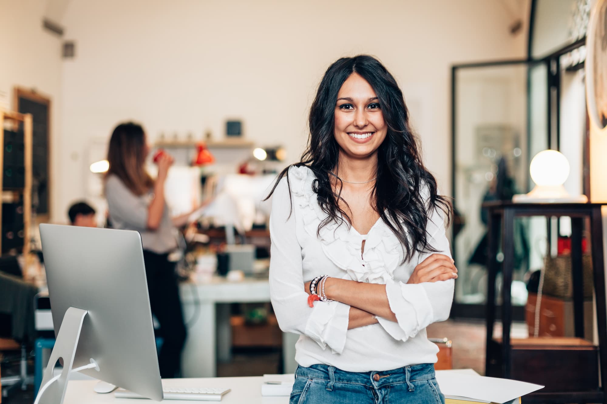 startup_costs A young woman stands in front of a busy office space after calculating her startup costs