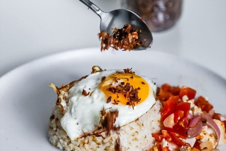 Manila Kitchen Adodo flakes being poured on a rice plus egg dish