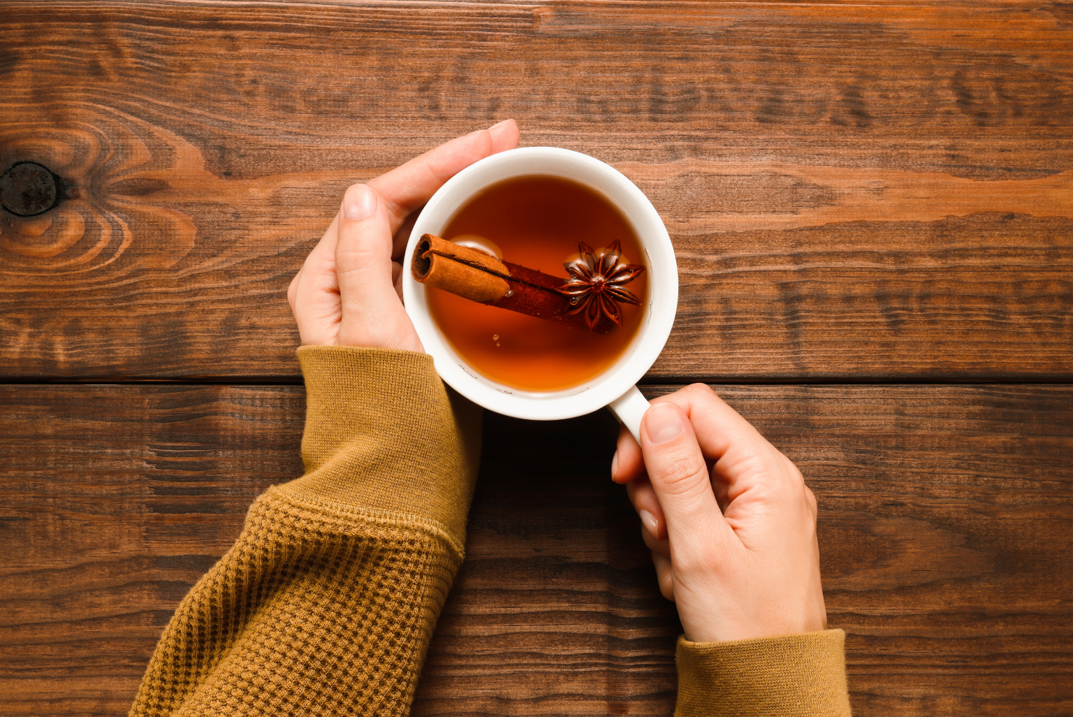 shutterstock_2061551240 (1) A woman holding a warm cup of tea with spices