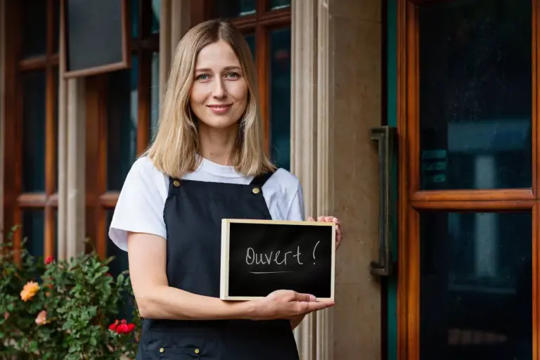 french-business-owner-holding-open-sign A French business owner holds a sign declaring her incorporated business open in Quebec